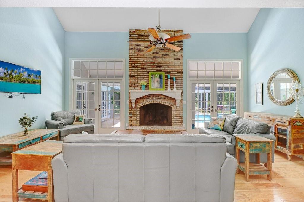 Hacienda style Great Room with hardwood floors, french doors and brick fireplace with custom mantle