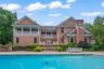 Expansive outdoor living area featuring a swimming pool, stone patio, and mature landscaping