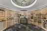 A collector’s sanctuary, this climate-controlled circular wine rotunda features floor-to-ceiling natural wood racking and elegant slate herringbone fl
