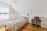 Bedroom featuring lofted ceiling, wood finished floors, radiator, a wainscoted wall, and a desk
