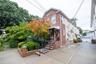 Brick and stucco exterior with multiple windows, a concrete driveway, and mature landscaping