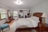 Spacious bedroom featuring wood-finish flooring, multiple windows with white blinds, a ceiling-mounted light fixture, and light-toned wall paint