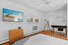 Bedroom with baseboard heating, a baseboard radiator, an AC wall unit, a ceiling fan, and wood finished floors