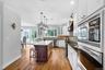 Kitchen featuring wood-finish flooring, white cabinetry, a dark wood-finish island with a light-toned countertop, and stainless steel built-in applian