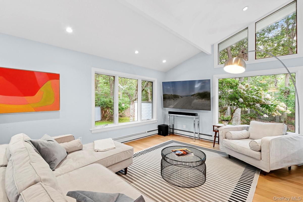Living room with a baseboard heating unit, light wood-style flooring, and recessed lighting