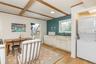 Laundry room with stacked washer / drying machine, beamed ceiling, and light wood finished floors