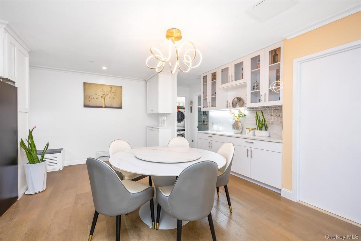 Dining room with stacked washer and clothes dryer, light wood-style floors, a chandelier, crown molding, and recessed lighting
