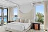 Bedroom with a water view, access to outside, beamed ceiling, and speckle patterned floor