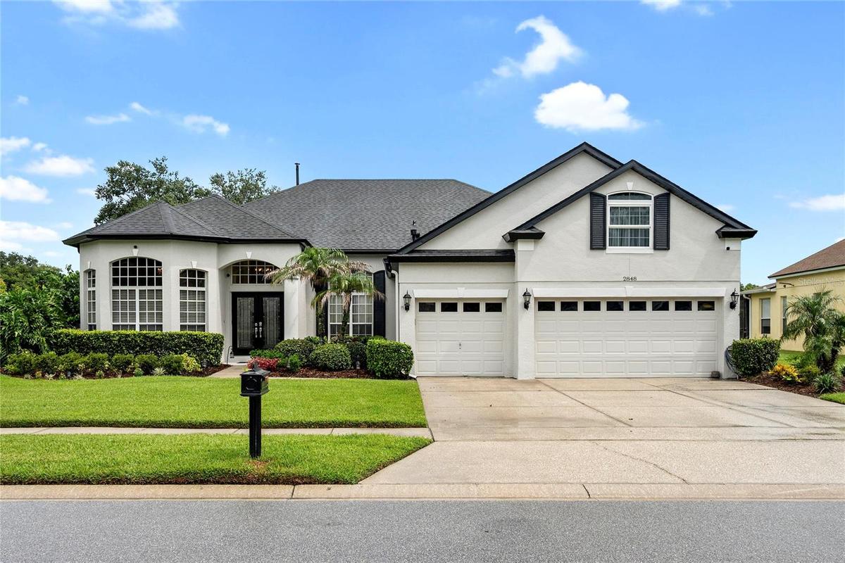 front with mature landscape and 3 car garage