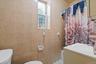 Bathroom featuring tiled walls, a window with security bars, a vanity with an integrated sink, a toilet, and tiled flooring