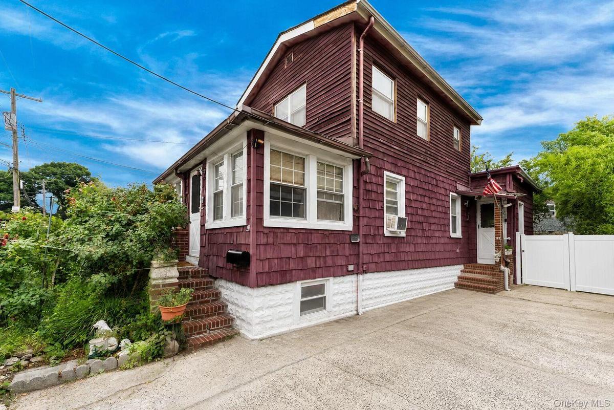 Two-story residence featuring deep red shingle and horizontal siding, white trim, and multiple windows