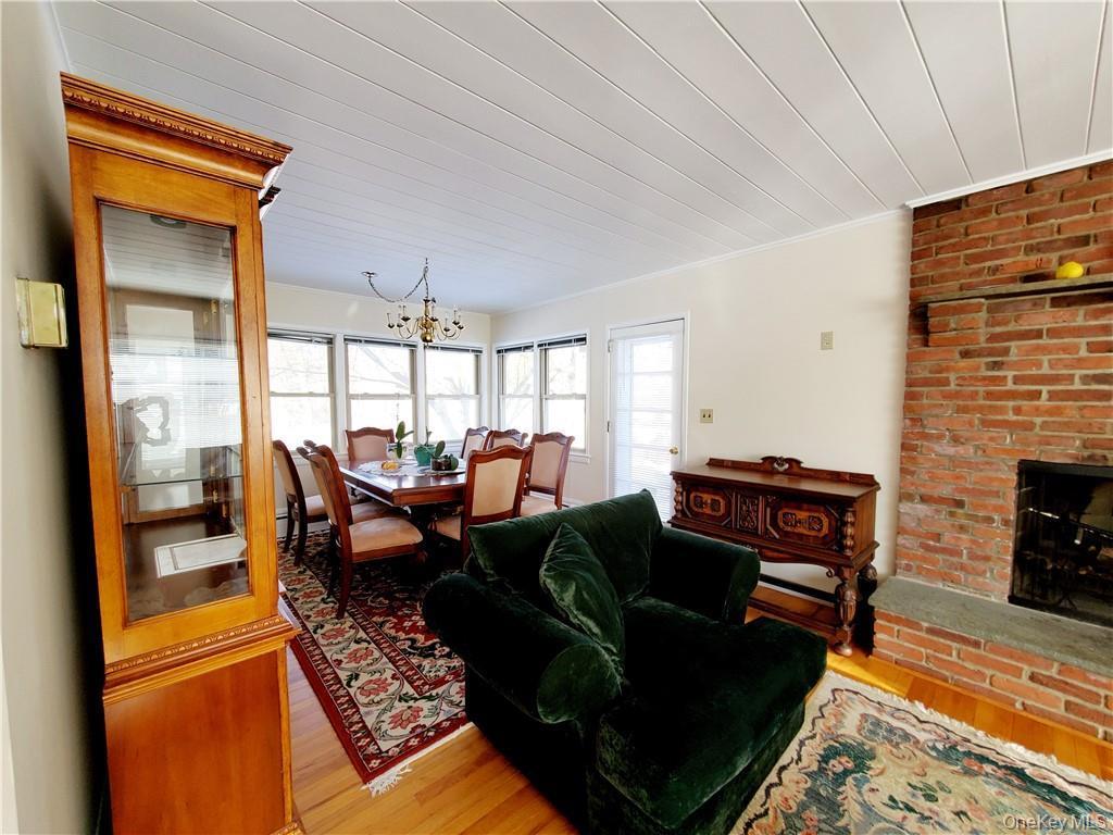 Living room featuring crown molding, light wood-style flooring, a brick fireplace, and a notable chandelier