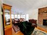 Living room featuring crown molding, light wood-style flooring, a brick fireplace, and a notable chandelier