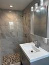 Bathroom with tile walls, vanity, tiled shower, and tasteful backsplash