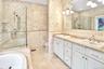 Full bathroom featuring tile walls, double vanity, a bathtub, a stall shower, and light tile patterned floors
