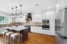 Kitchen featuring hardwood flooring, a central island with a light-toned countertop, white cabinetry, a built-in microwave and oven, and stainless ste