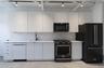 Kitchen with black appliances, modern cabinets, decorative backsplash, and white cabinetry