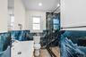 Bathroom featuring blue wave-patterned wall tiling, a glass-enclosed shower with a pebble-tiled floor, and a white vanity with a single basin and a ma