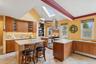 Kitchen with a skylight, brown cabinets, range with two ovens, island exhaust hood, and decorative backsplash