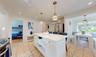 Kitchen featuring stainless steel appliances, white cabinetry, hanging light fixtures, and radiator