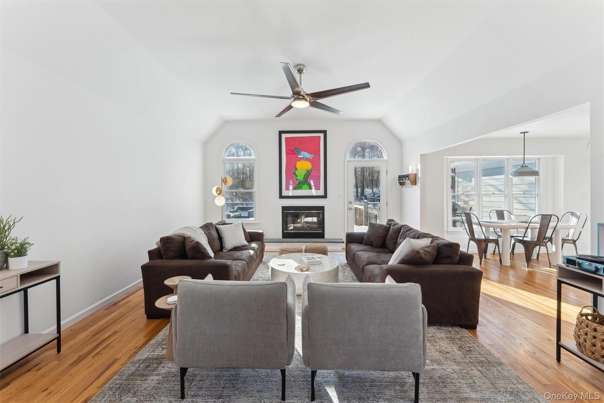Living area with  a ceiling fan,wood flooring, a fireplace, and vaulted ceiling