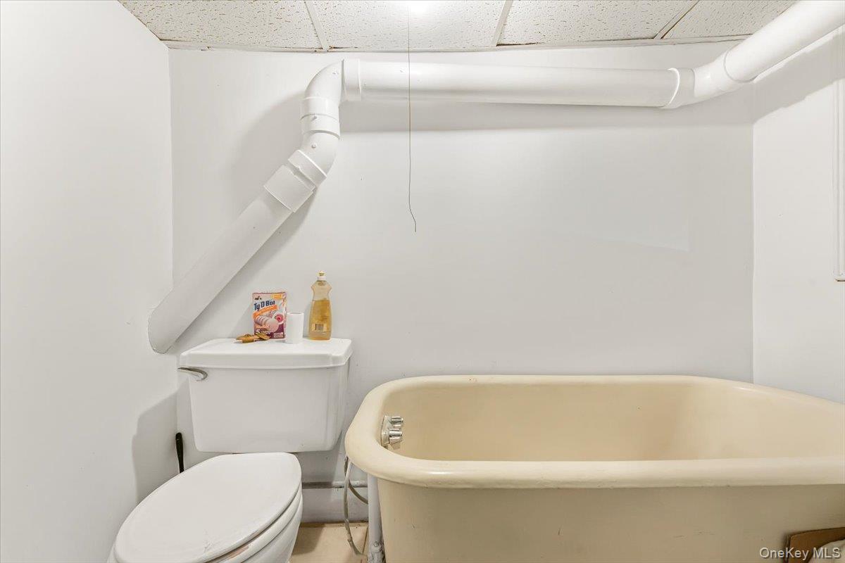 Full bathroom featuring toilet, a freestanding tub, and a paneled ceiling