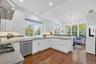 Kitchen with wall chimney exhaust hood, white cabinets, backsplash, dark wood finished floors, and lofted ceiling