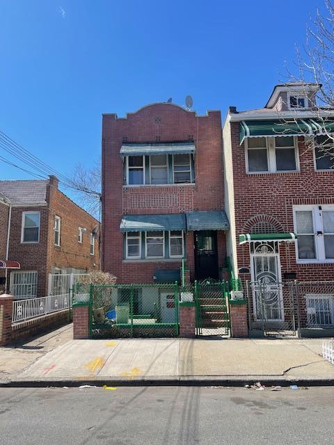 View of property with brick siding, a fenced front yard, and a gate