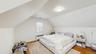 Bedroom with visible vents, radiator heating unit, vaulted ceiling, and wood finished floors