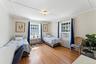 Bedroom with radiator heating unit, wood finished floors, cooling unit, and ornamental molding