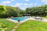 Outdoor pool with a patio area, a yard, view of scattered trees, and outdoor lounge area