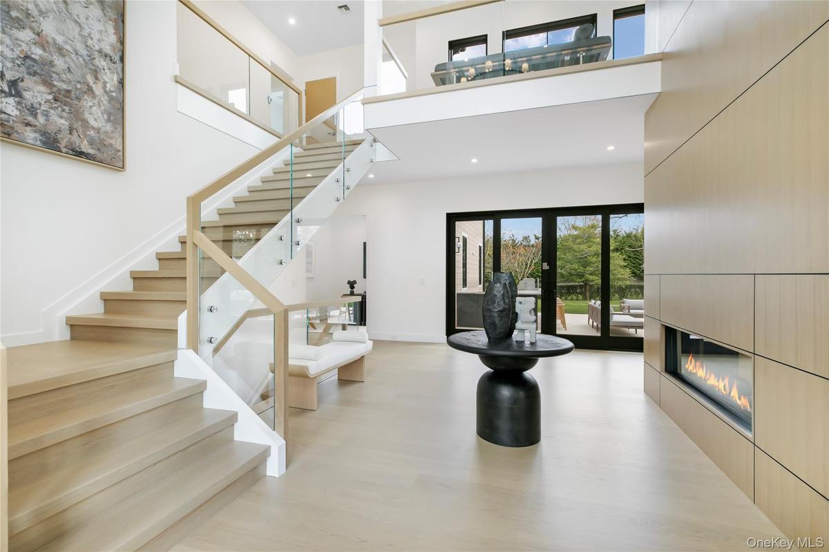 Stairs featuring a high ceiling, a glass covered fireplace, recessed lighting, and wood finished floors