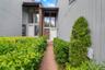 Brick walkway bordered by manicured hedges leading to two distinct entryways