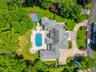 Expansive property featuring a large residence with a multi-level roofline, a winding driveway with paver accents, an integrated swimming pool with a 