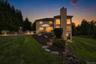 Extensive backyard with a manicured lawn, a stone retaining wall, and a multi-level patio featuring a built-in kitchen/grill station