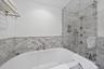 Bathroom featuring a garden tub, a stall shower, and tile walls