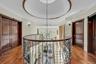 Hallway with an upstairs landing, wood finished floors, crown molding, a raised ceiling, and a chandelier