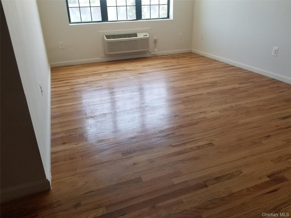 Spare room with light wood-type flooring and an AC wall unit