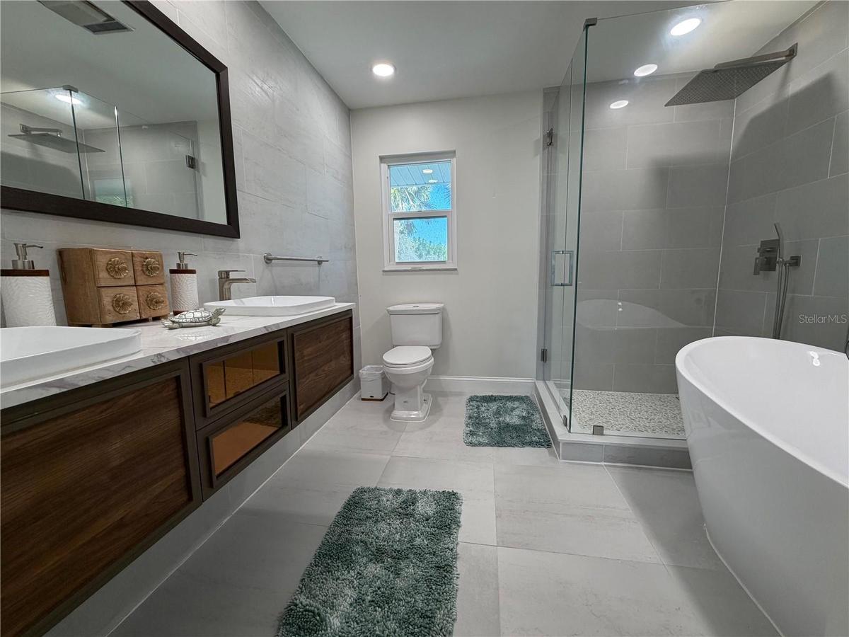 Primary bath with dual vanity, walk-in shower, and soaking tub.