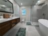Primary bath with dual vanity, walk-in shower, and soaking tub.