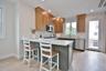 Kitchen with backsplash, a kitchen breakfast bar, light stone counters, stainless steel appliances, and light wood-style floors