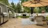 Wooden terrace with a fenced backyard, grilling area, outdoor dining space, and view of wooded area
