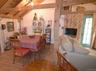 Spacious room featuring exposed wood ceiling beams, wood-finish flooring, and a whitewashed brick accent wall