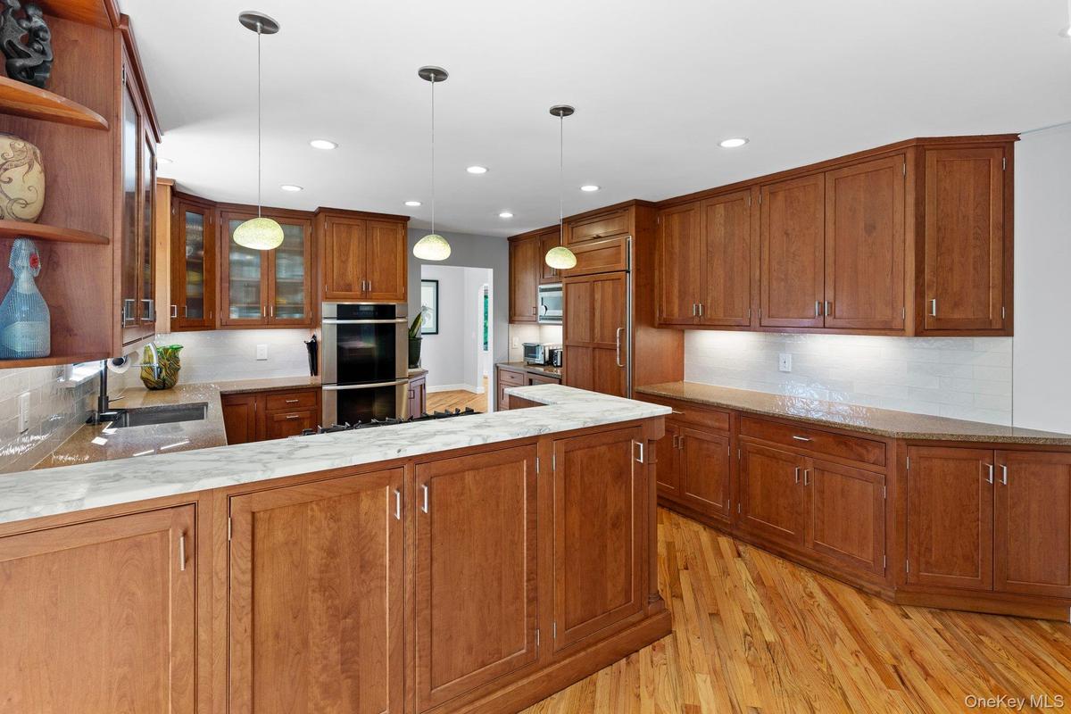 Kitchen featuring open shelves, brown cabinetry, a sink, and stainless steel double oven