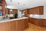 Kitchen featuring open shelves, brown cabinetry, a sink, and stainless steel double oven
