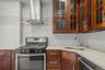 Kitchen featuring stainless steel appliances, range hood, light stone countertops, glass insert cabinets, and tasteful backsplash