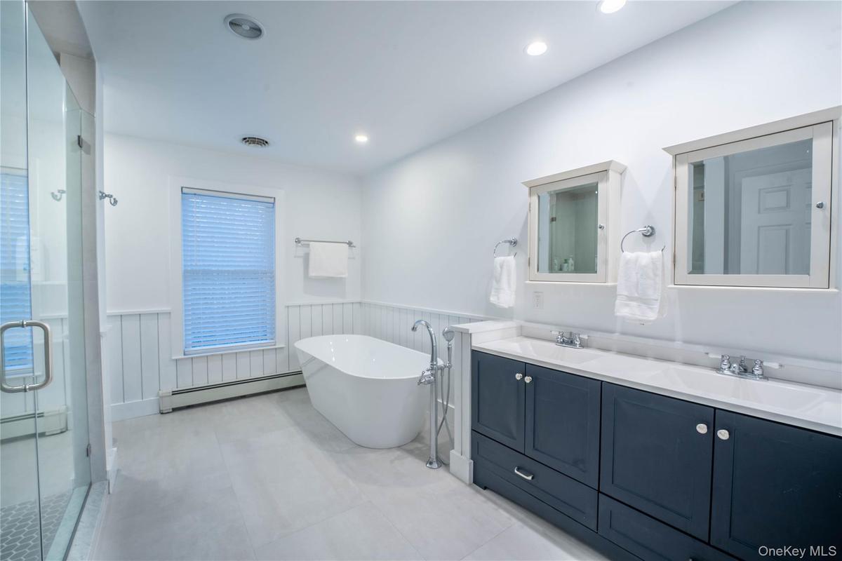 Bathroom featuring a baseboard heating unit, wainscoting, a sink, and visible vents