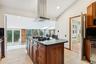 Kitchen with dark stone countertops, island range hood, lofted ceiling, recessed lighting, and a kitchen island