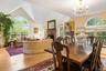 Dining room with a brick fireplace, light wood-type flooring, a chandelier, and high vaulted ceiling