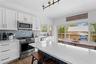 Kitchen featuring appliances with stainless steel finishes, a breakfast bar, tasteful backsplash, light stone countertops, and wood finished floors